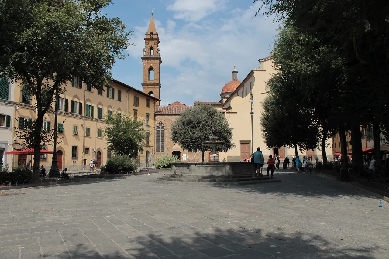 Piazza Santo Spirito with trees, a fountain and the basilica's bell tower