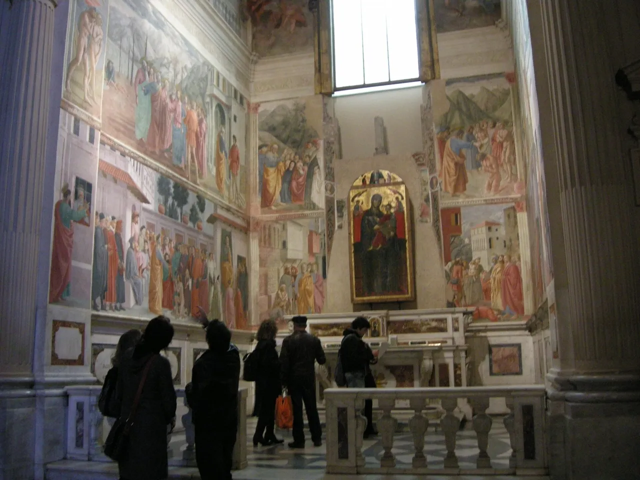 A small group of visitors at the marble altar rail of the Brancacci Chapel